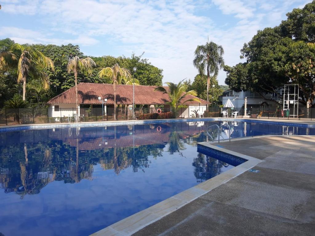 a large swimming pool with a building in the background at Descansa en familia en Rio Bonito lleva tus mascotas in Melgar