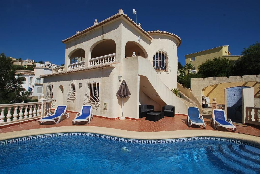 Cette villa dispose d'une piscine avec des chaises longues bleues. dans l'établissement Villa Higeron, à Cumbre del Sol