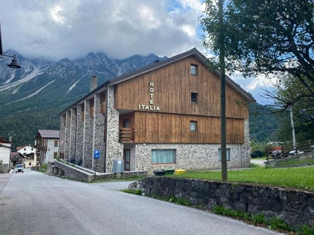 um grande edifício de madeira ao lado de uma estrada em HOTEL ITALIA em Forni di Sopra