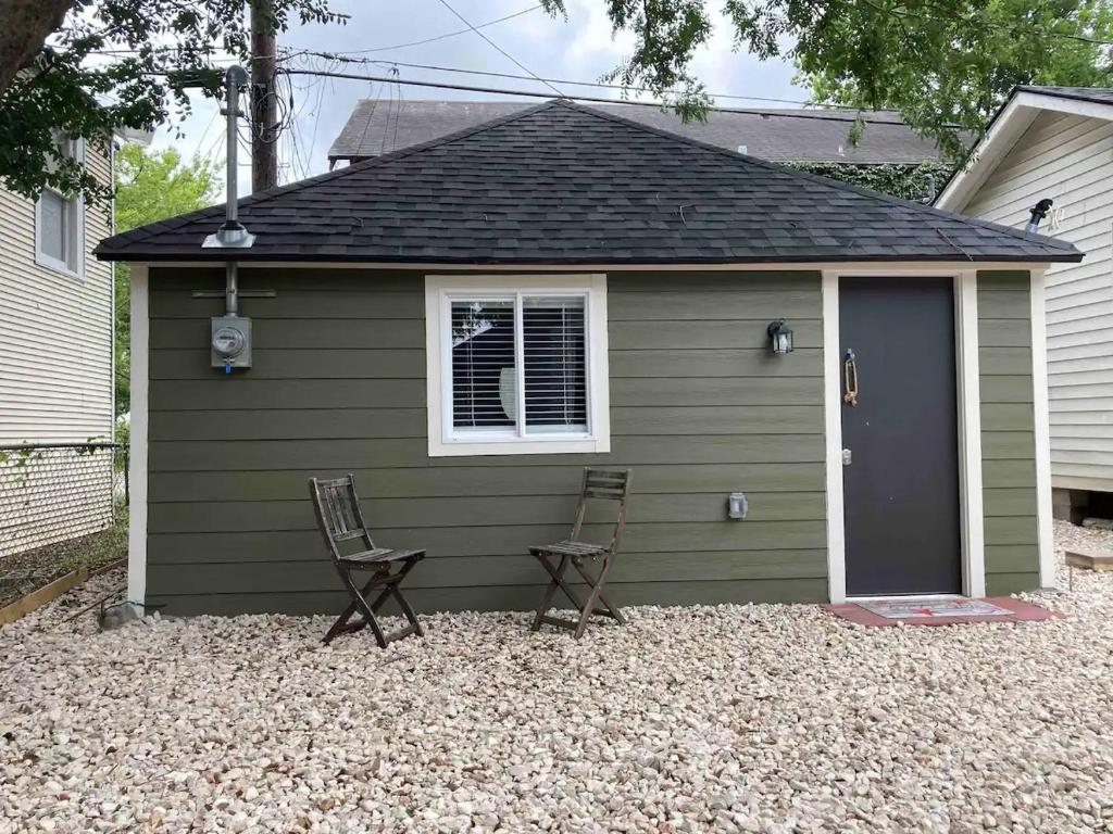 a small green shed with two chairs and a door at The GREEN Tiny House in Houston