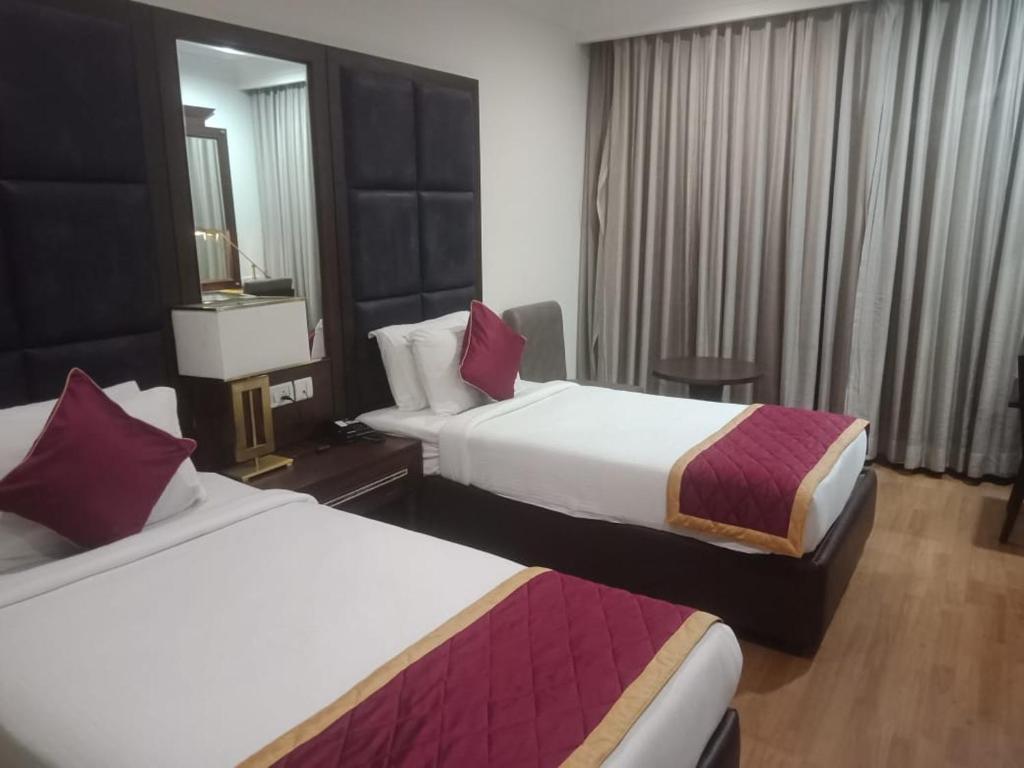 a hotel room with two beds and a mirror at Hotel Comfortel Banjara Hills- Free Buffet breakfast- Multi Cuisine Restauran- An Svm Brand in Hyderabad