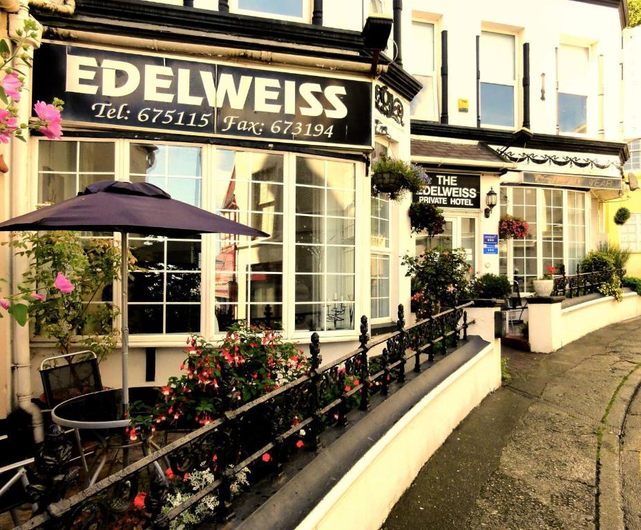 a restaurant with an umbrella and flowers in front of it at Edelweiss Guest House in Douglas