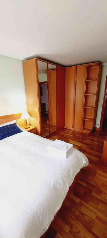 1 dormitorio con cama blanca y armarios de madera en HABITACIÓN EN BILBAO, en Bilbao
