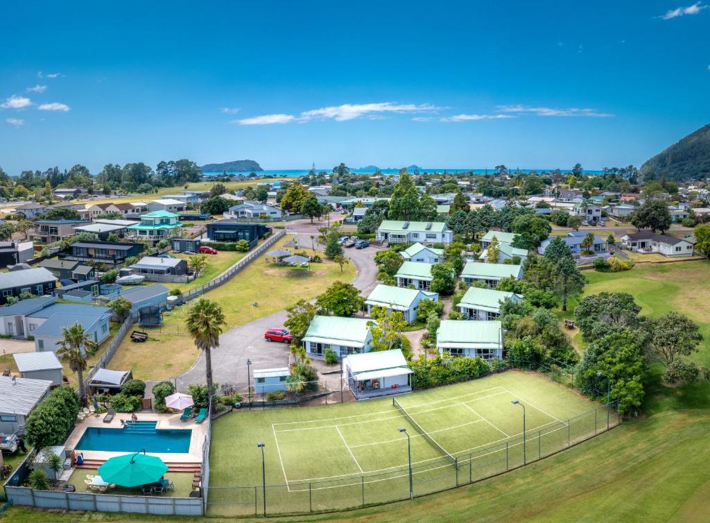 eine Luftansicht eines Wohngebäudes mit einem Tennisplatz in der Unterkunft Pauanui Pines Motor Lodge in Pauanui