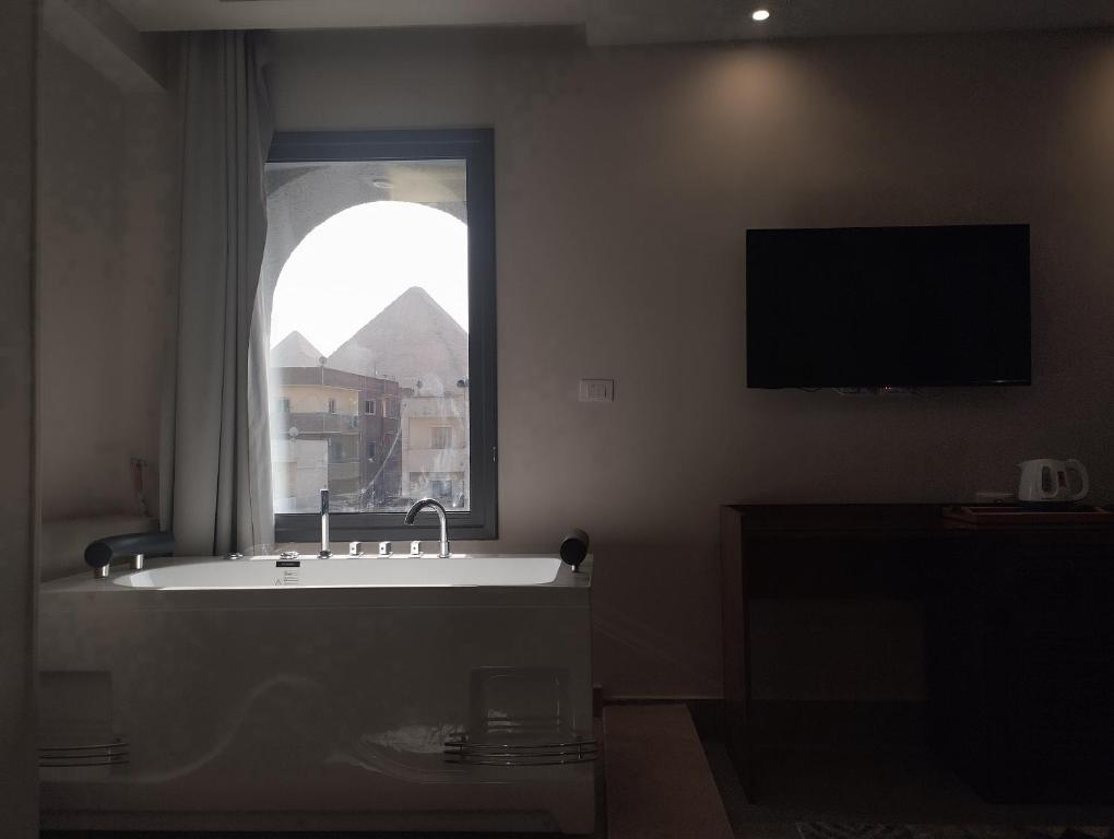 uma casa de banho com uma banheira e uma janela em Zahira Pyramids View em Cairo