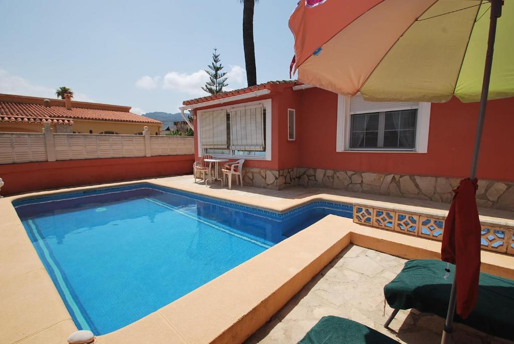 a swimming pool with an umbrella and a house at Holidayhome Melodia in Denia