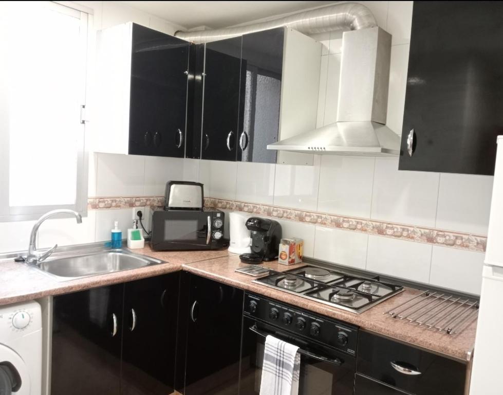 una cucina con armadi neri, lavandino e piano cottura di Apartamento exterior de tres habitaciones a Valencia