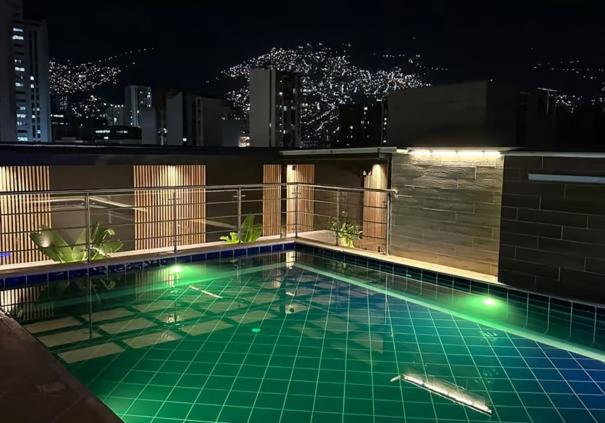 a swimming pool with lights on a building at night at Hotel California Center in Medellín