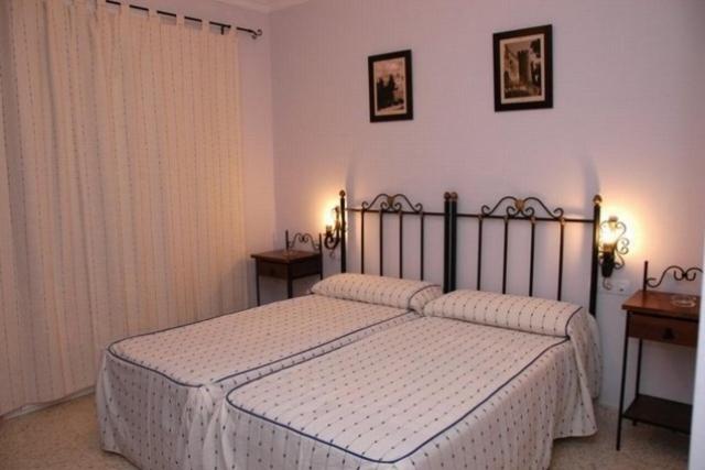 um quarto com uma cama com lençóis brancos e duas mesas em Hotel Don Juan em El Coronil