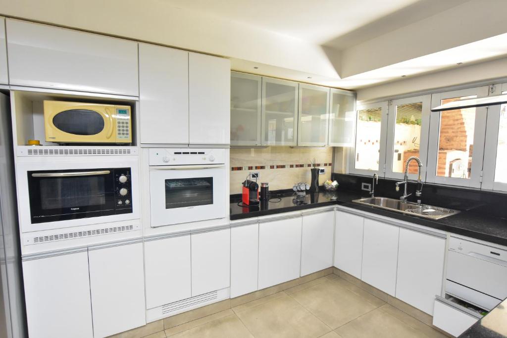 uma cozinha branca com armários brancos e um micro-ondas em Casa Relax em Presidencia Roque Sáenz Peña