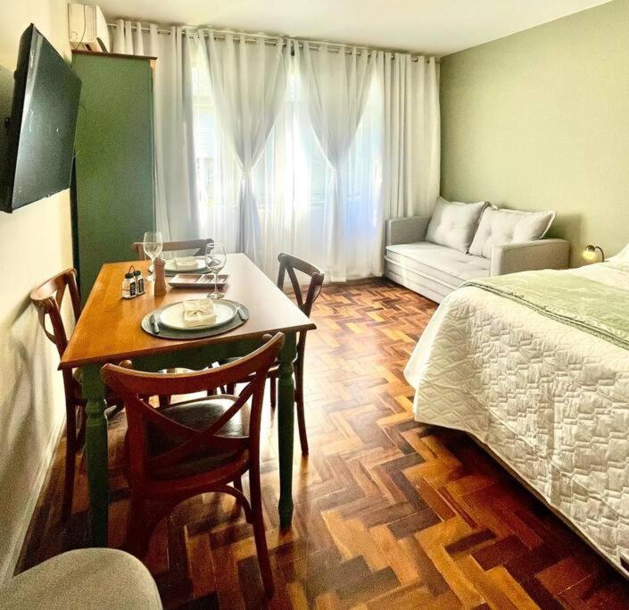 a room with a table and a bed and a table and chairs at Loft aconchegante no Menino Deus in Porto Alegre