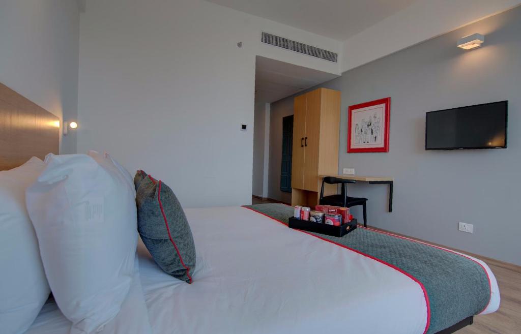 a bedroom with a white bed with a flat screen tv at Townhouse 271 De Alphabet in Hyderabad