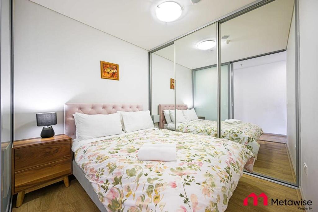 1 Schlafzimmer mit 2 Betten und einem Spiegel in der Unterkunft MetaWise Burwood Westfield Cozy 2Bed Free Parking VT109 in Sydney