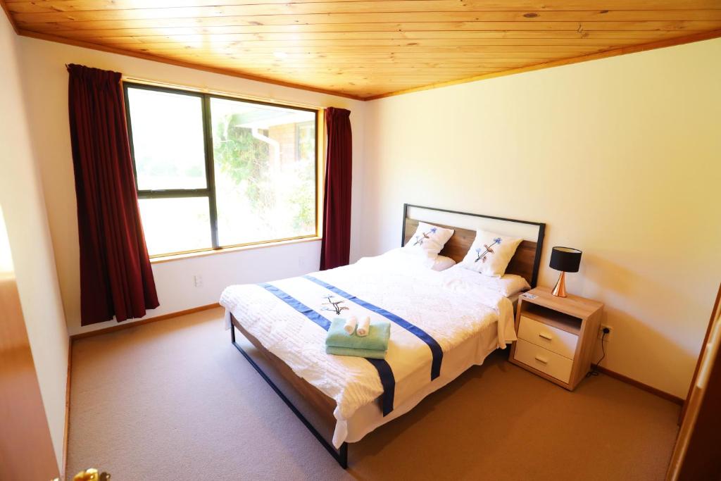 ein Schlafzimmer mit einem Bett und einem großen Fenster in der Unterkunft Miranda Farm - Away from city, surrounded by animals in Kaiapoi
