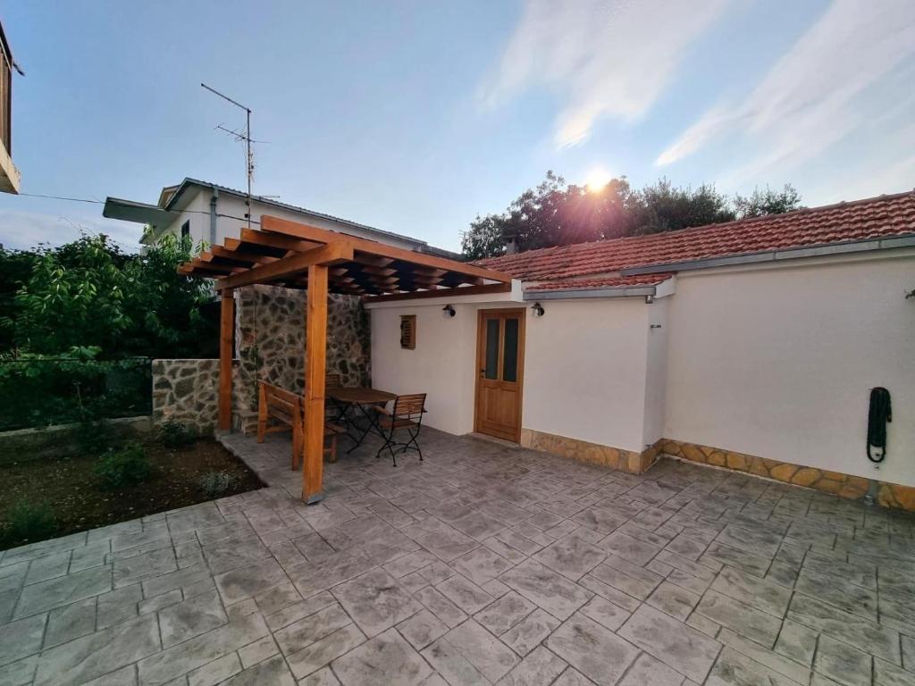 a patio with a wooden pergola next to a house at Apartments by the sea Rogoznica - 22448 in Rogoznica
