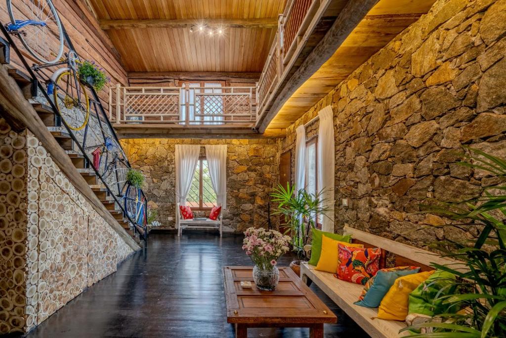 a living room with a couch and a stone wall at Jml villa foresta in Kalawana