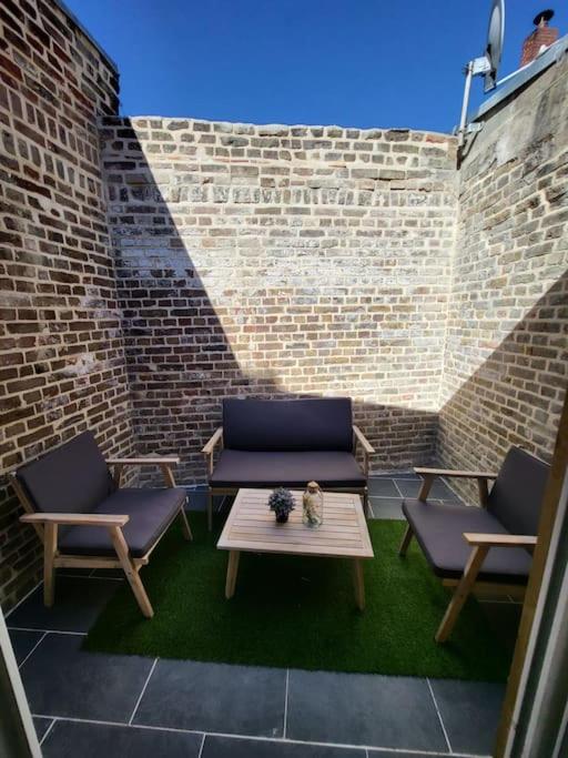 d'une terrasse avec 2 chaises, une table et un mur en briques. dans l'établissement appartement cosy et chaleureux, à Amiens