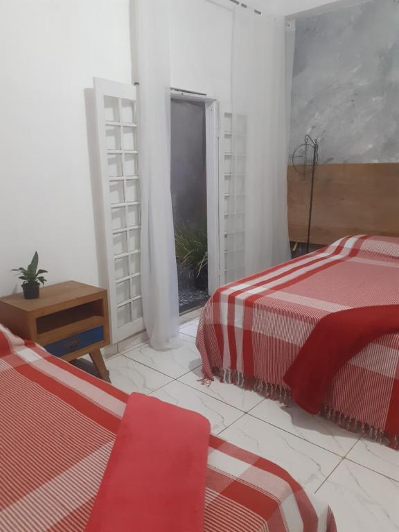 Cette chambre blanche dispose de deux lits et d'une fenêtre. dans l'établissement Vilarejo do aconchego, à Santa Cruz de Minas
