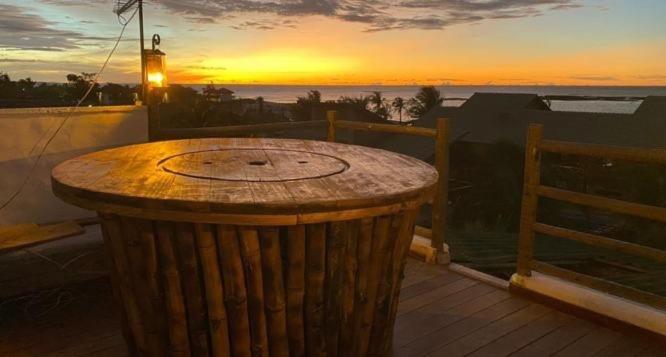 a clock on a deck with a sunset in the background at Bali BG Casa Bamboo in Barra Grande