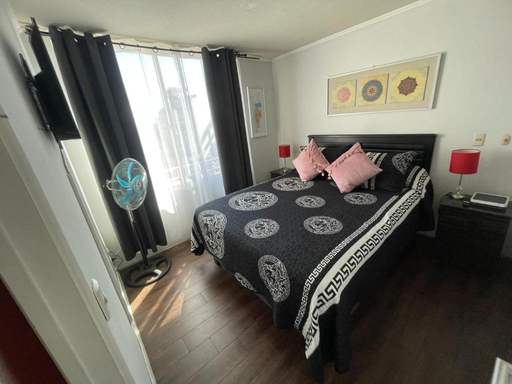 um quarto com uma cama preta e branca com almofadas cor-de-rosa em alojamiento city em Santiago