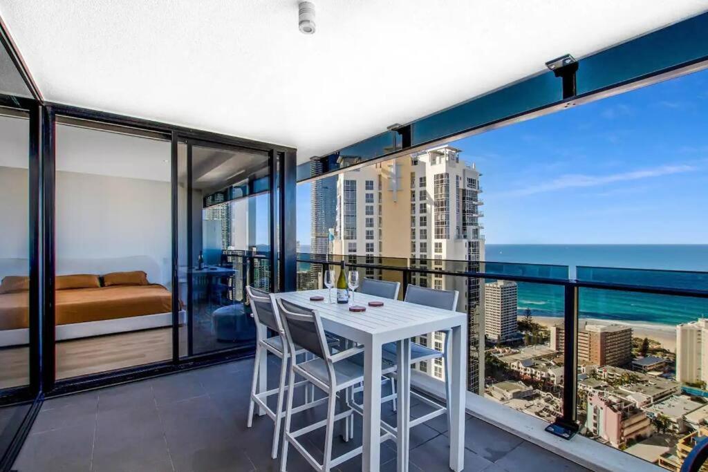 Cette chambre dispose d'un balcon avec une table et des chaises blanches. dans l'établissement NEW! - Circle On Caville 33rd Floor Apartment Ocean Views, à Gold Coast