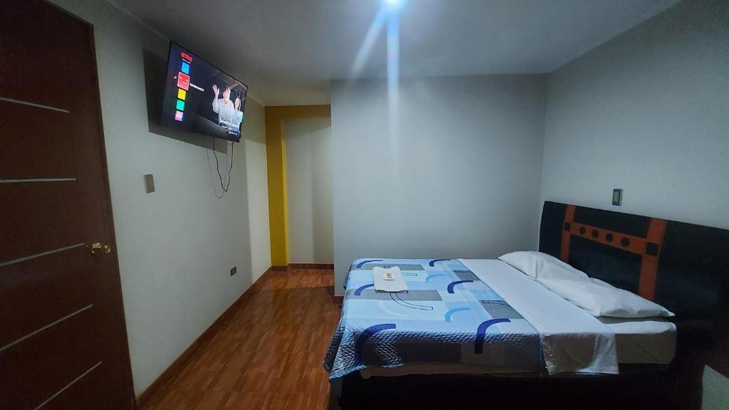 a bedroom with a bed with a tv on the wall at SOL DEL NORTE in Ayacucho