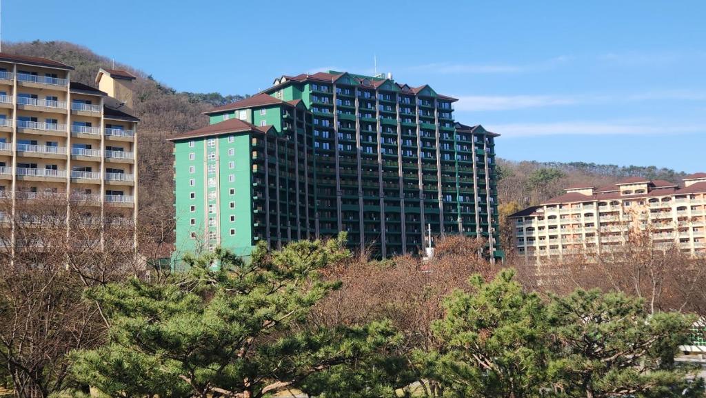un edificio alto y verde frente a algunos edificios en Sono Calm Vivaldi Park, en Hongcheon