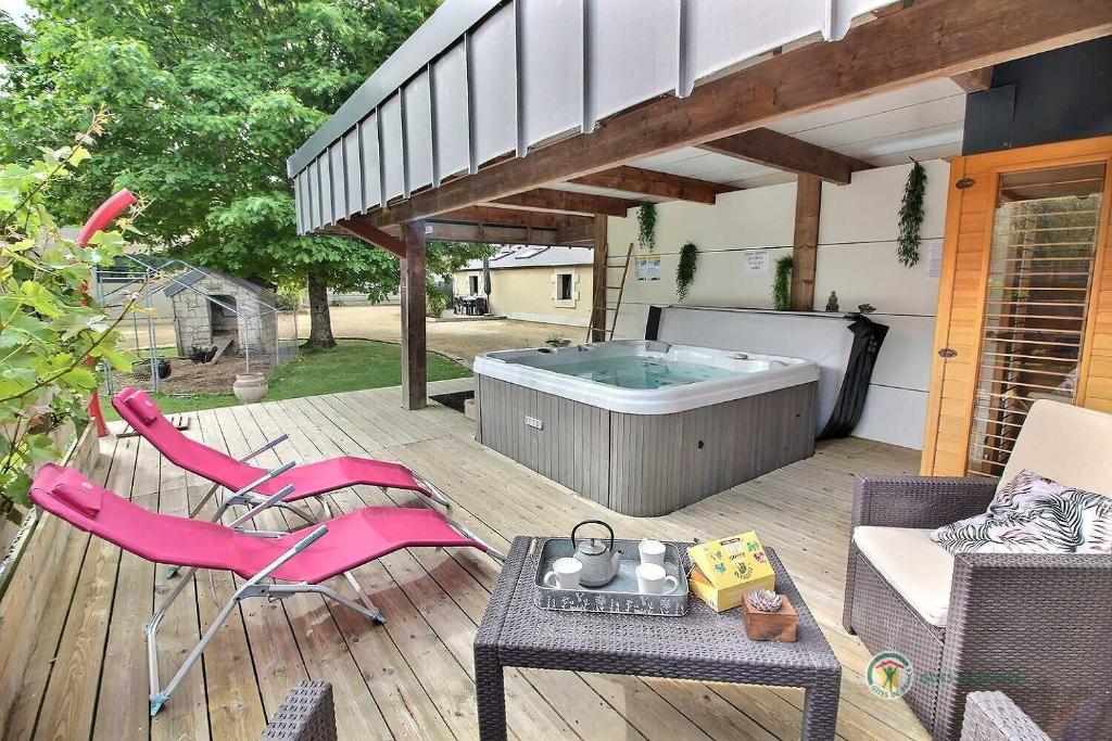 une terrasse avec un bain à remous, une table et des chaises dans l'établissement Melina, à Lanvollon