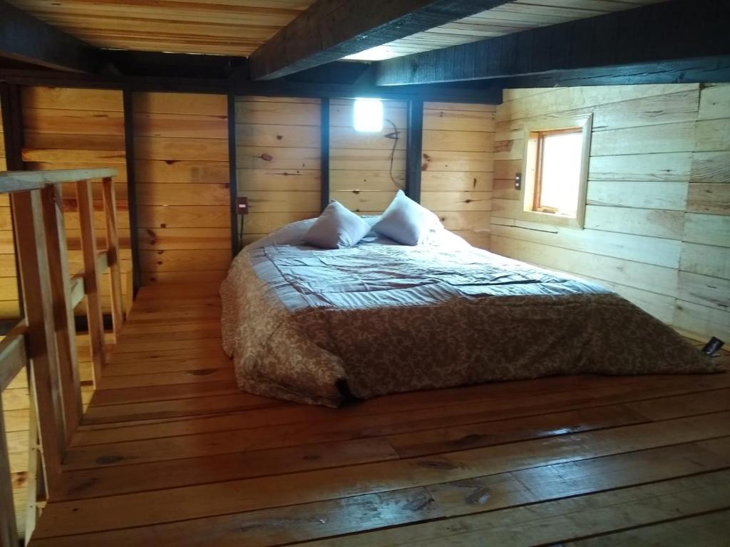 1 dormitorio con 1 cama en una cabaña de madera en CABAÑA MINCHY, en Mazamitla