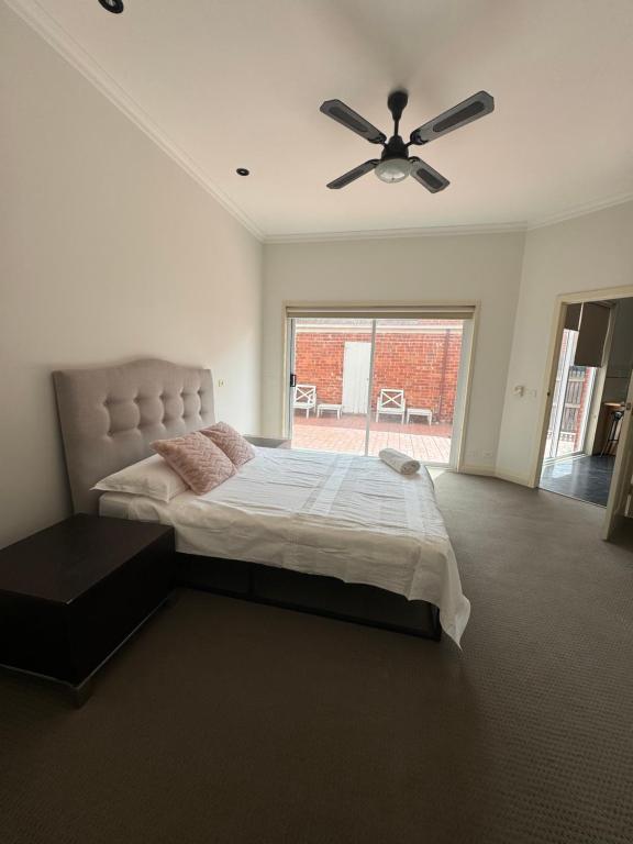 een slaapkamer met een bed en een plafondventilator bij Bentleighs Magnificent Beautifully renovated and extended 1920s period family home. in Melbourne