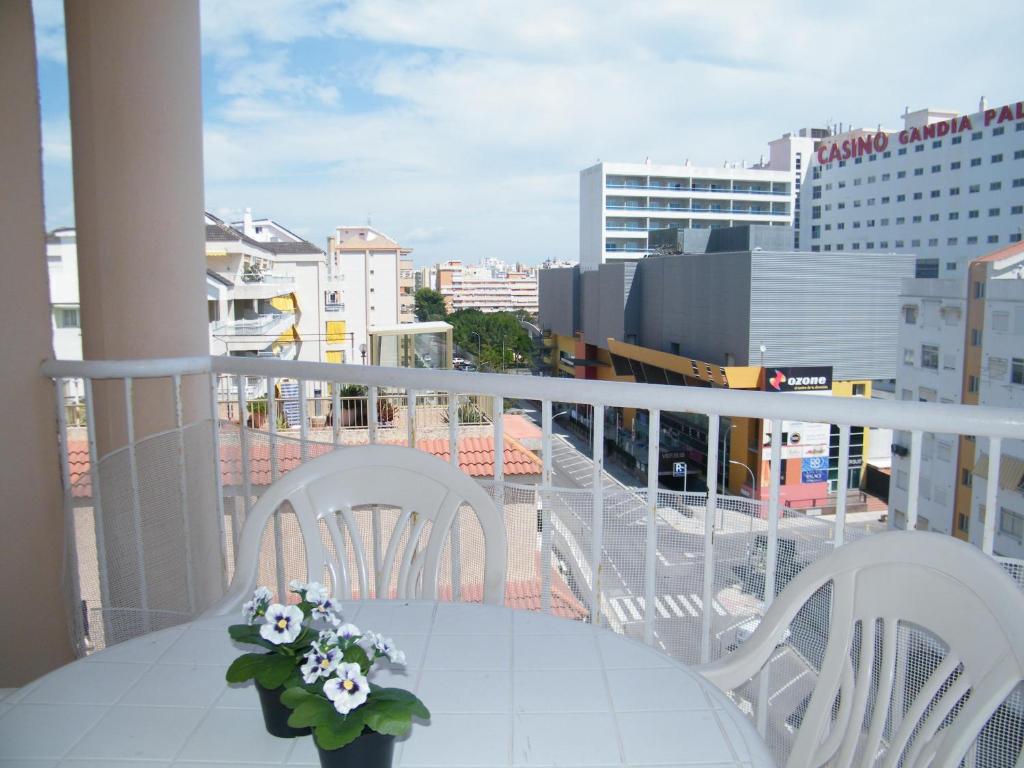 a table with chairs and a vase of flowers on a balcony at Apartamento Playa de Gandía, 3 dormitorios, 7 personas - ES-314-11 in Gandía