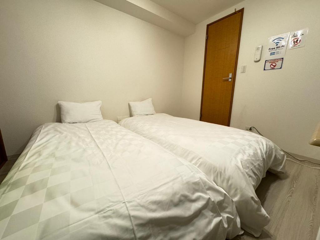 dos camas sentadas una al lado de la otra en una habitación en マルチステイ大阪京橋21 en Osaka