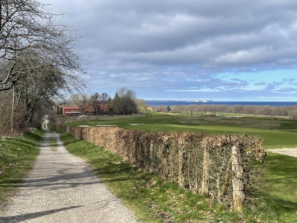 a dirt road next to a stone wall and a golf course at Modernes Architektenhaus direkt am Golfplatz Schloss Ranzow. in Lohme