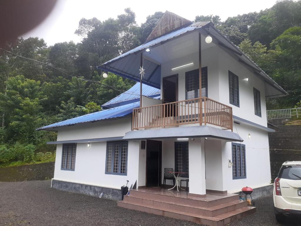 a white house with a balcony on top of it at Oasis villa in Vagamon