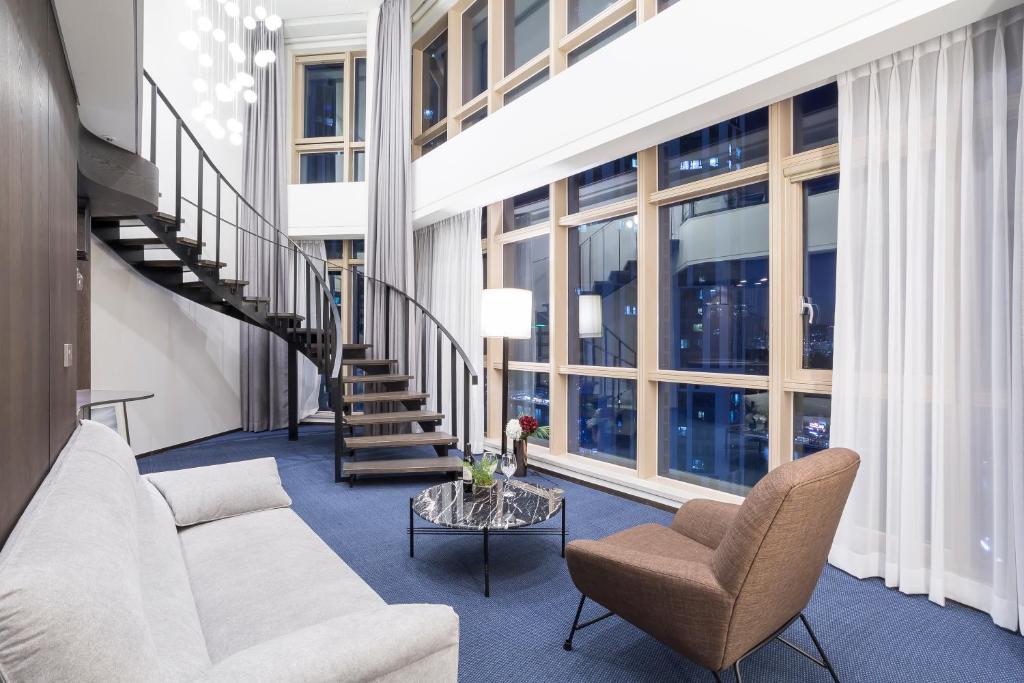 a living room with a couch and chairs and a staircase at Centum Prime Hotel in Busan