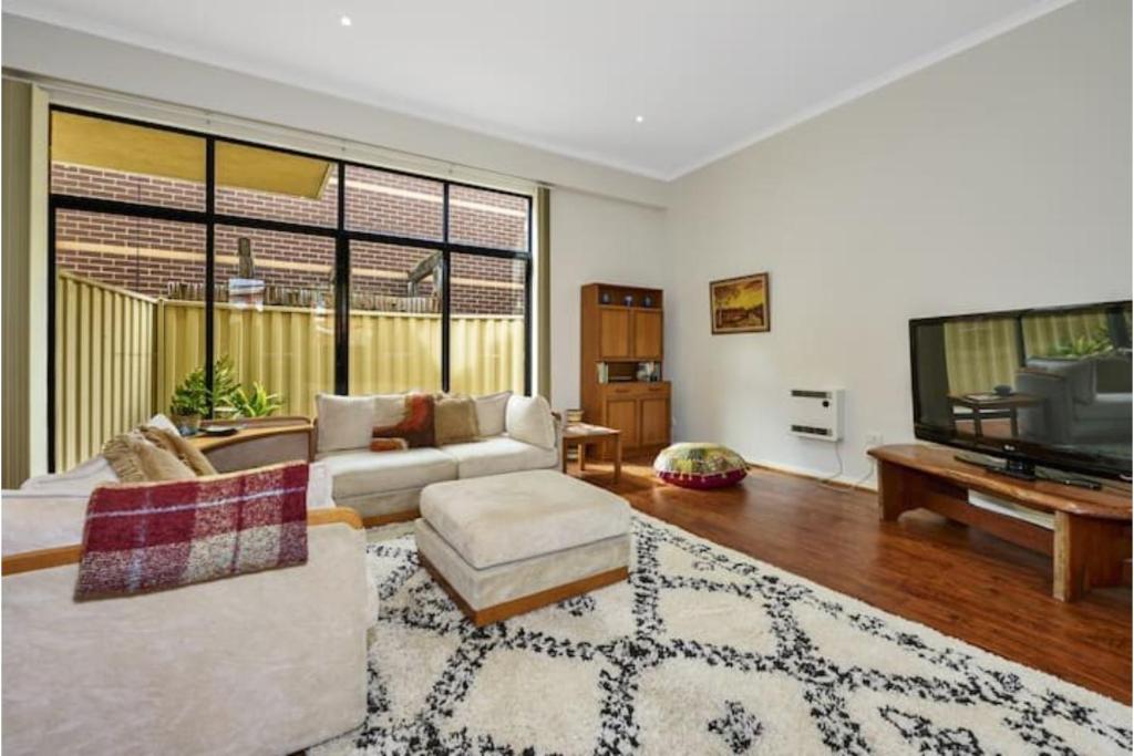 sala de estar con sofá y TV de pantalla plana en Bright & Eclectic Home - Footscray VIC, en Melbourne