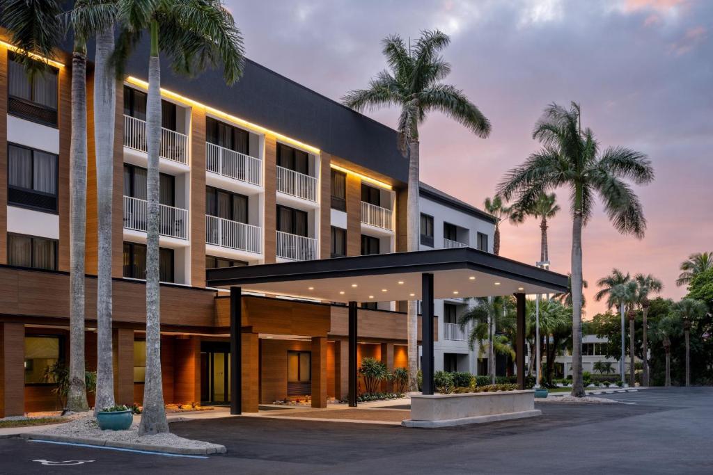 an exterior view of a hotel with palm trees at Courtyard by Marriott - Naples in Naples