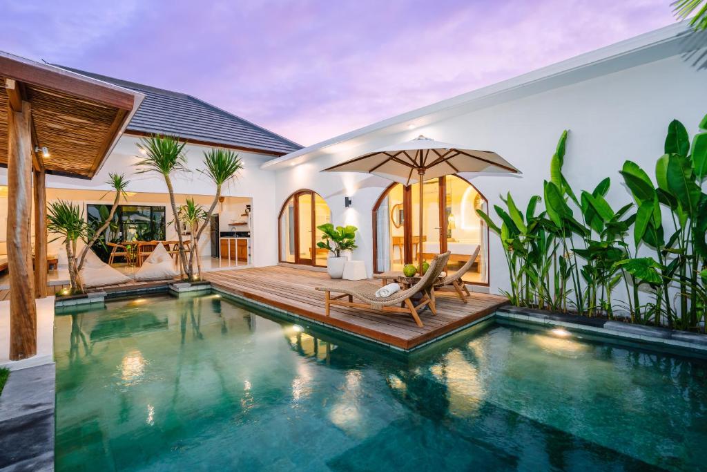 una piscina en una villa con silla y sombrilla en Villa Emilia, en Tanah Lot