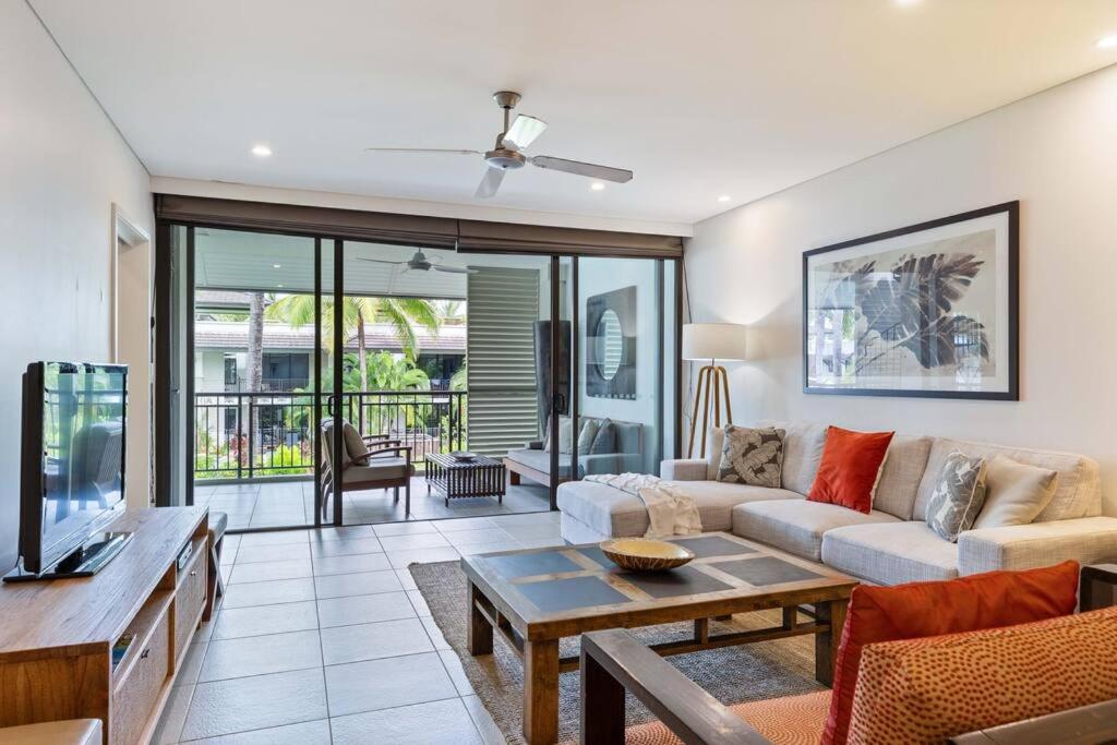 een woonkamer met een bank en een tv bij Devine Rooftop Penthouse at Temple Resort in Port Douglas