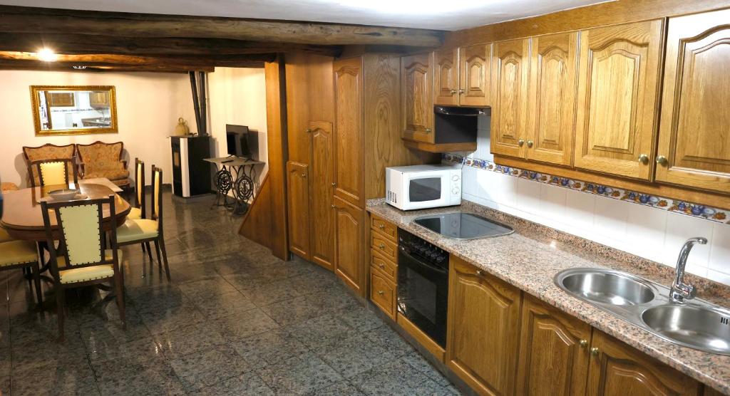 a kitchen with wooden cabinets and a sink and a microwave at A CASA DO POZO in Folgoso