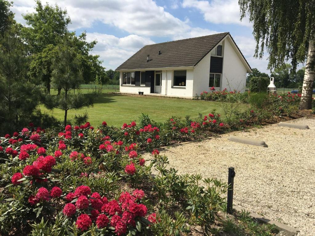 uma casa branca com flores vermelhas no quintal em Cozy Holiday Home in Nistelrode with Garden em Nistelrode