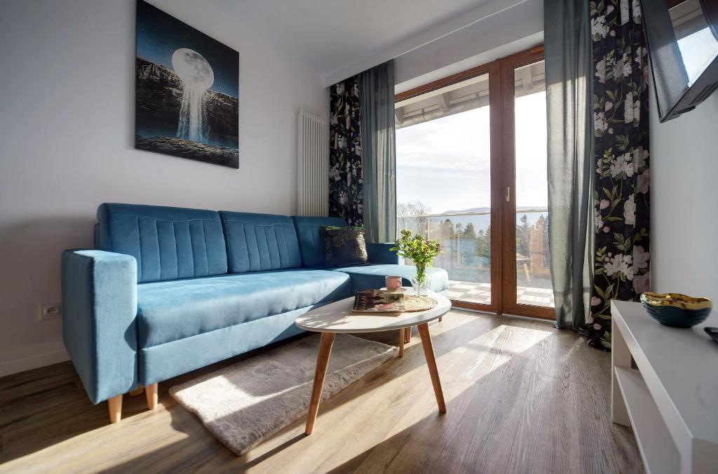 een woonkamer met een blauwe bank en een tafel bij Trevilles Apartamenty Nice View in Szklarska Poręba