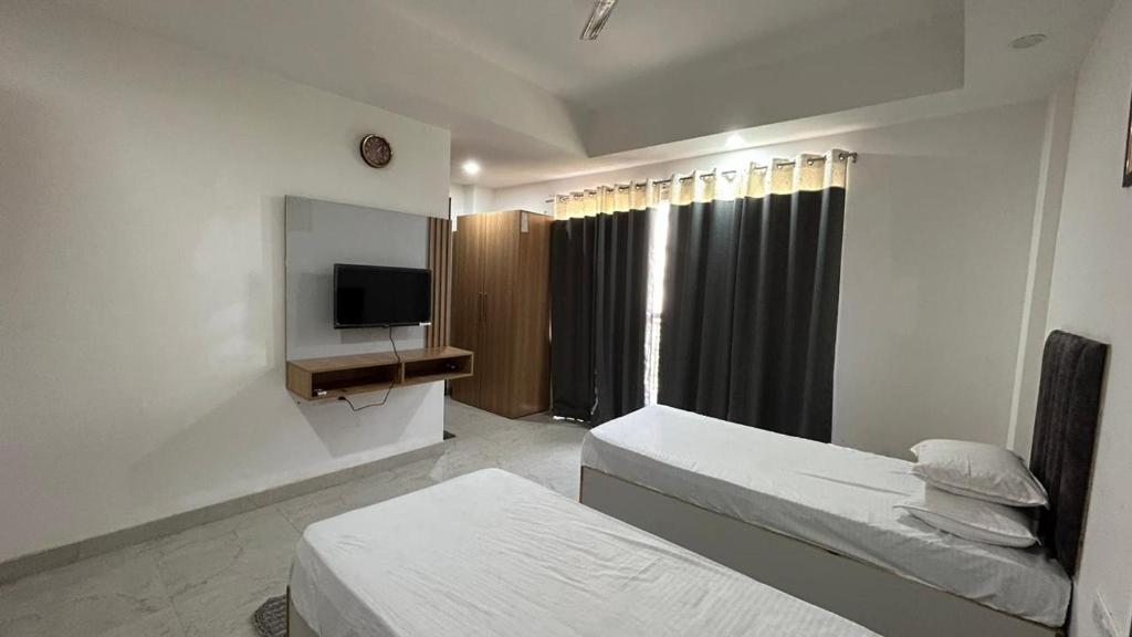 a hotel room with two beds and a television at Happy Living in Noida