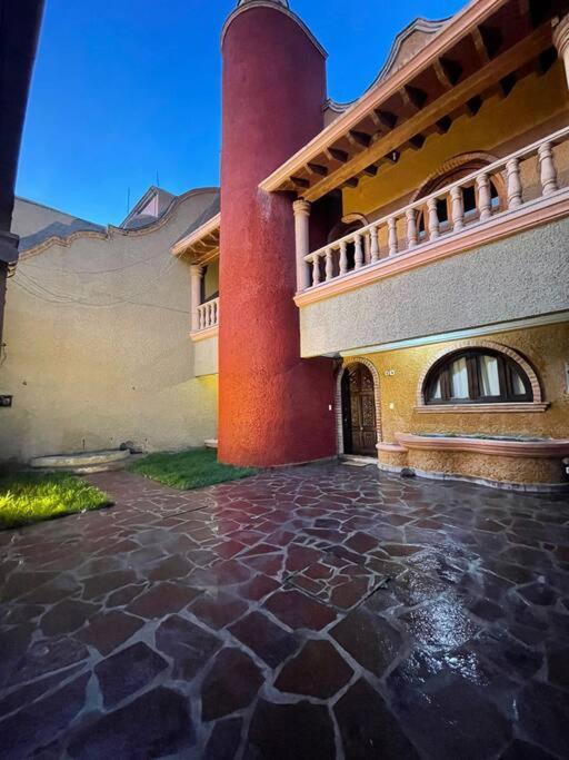 a large house with a brick courtyard with a tower at Casa Orquidea in San Miguel de Allende