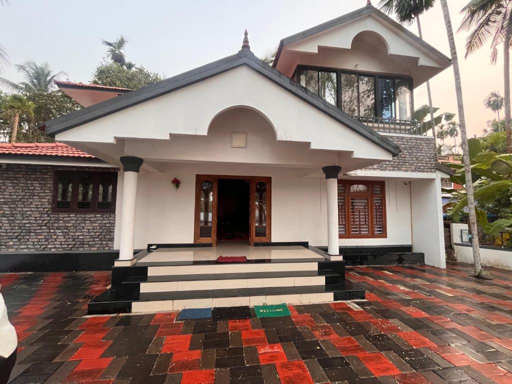ein kleines weißes Haus mit schwarzem und rotem Fliesenboden in der Unterkunft Manasam Homes in Kunnamangalam