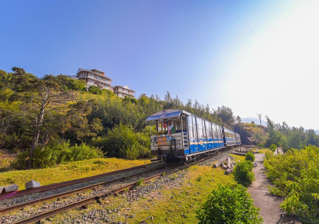 Un tren azul viajando por las vías de una colina en Kanavu Valley View Premium 4 Star Resort Ooty by VOYE HOMES, en Ooty