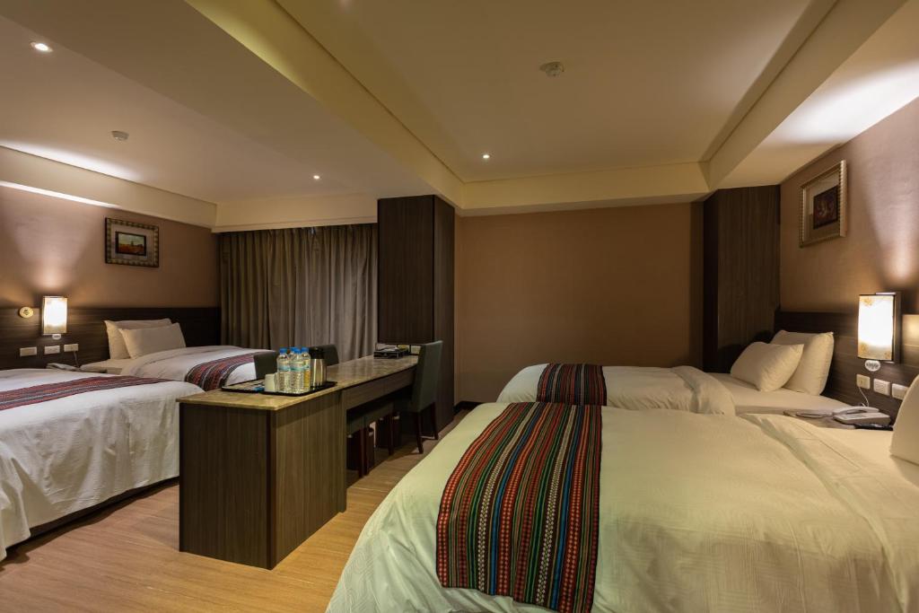 a hotel room with two beds and a desk at Royal Guest Hotel in Tainan