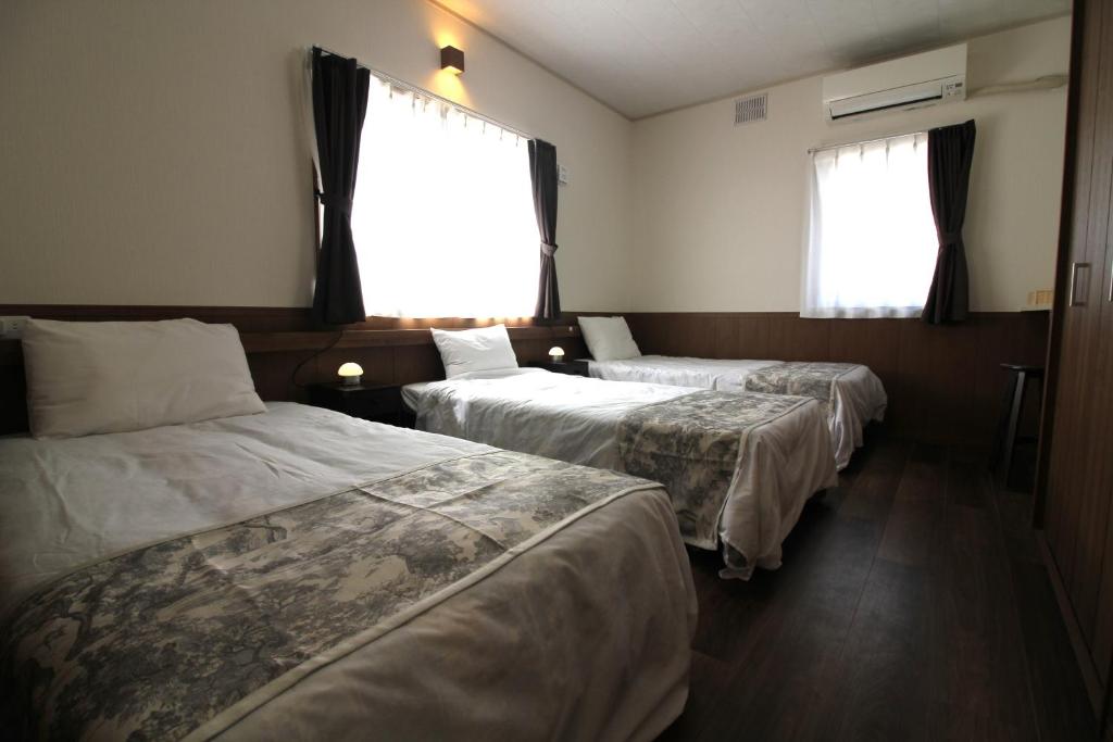 Cette chambre comprend trois lits et deux fenêtres. dans l'établissement Sea Breeze Sumuide 沖縄, à Nago
