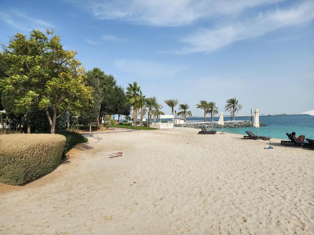 a sandy beach with palm trees and the ocean at Harf3502 Luxurious Large Studio in Abu Dhabi