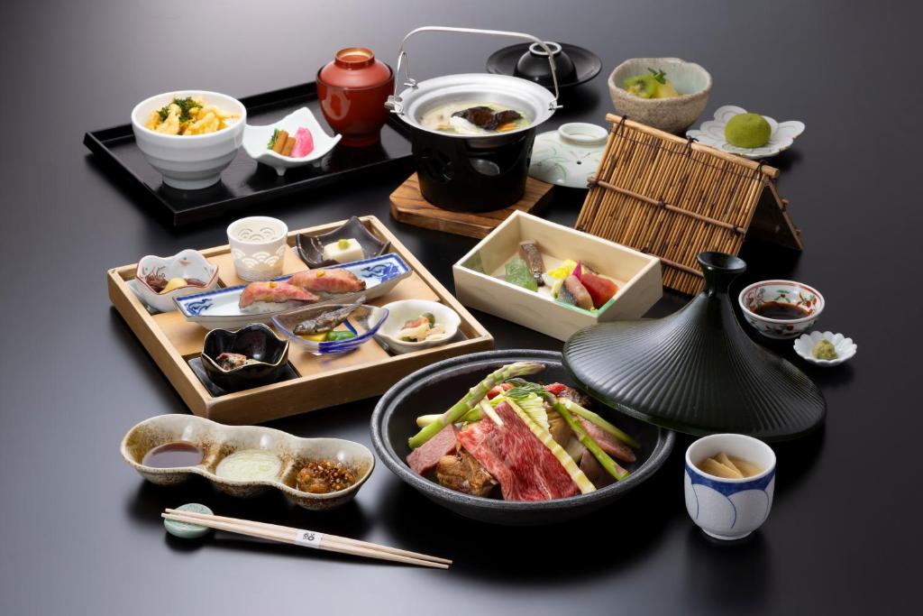 Onyado Yuinosho في شيراكاوا: طاولة مليئة بأطباق الطعام وأوعية الطعام
